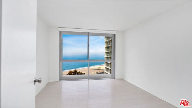 unfurnished room featuring expansive windows, a healthy amount of sunlight, and a water view