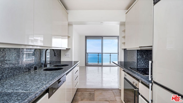 kitchen with sink, stainless steel oven, white cabinets, and tasteful backsplash