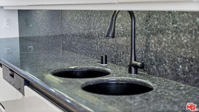 room details with white cabinetry, tasteful backsplash, and sink