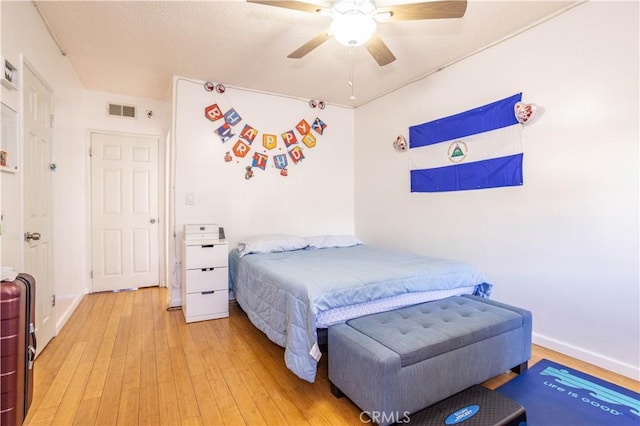 bedroom featuring light wood-style flooring, baseboards, ceiling fan, and visible vents