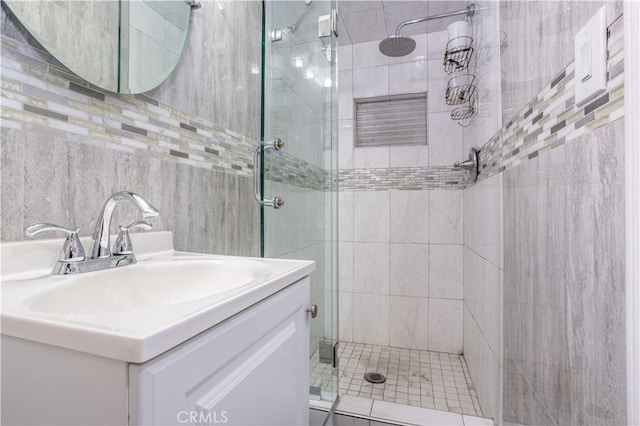 full bathroom with a stall shower, tile walls, and vanity