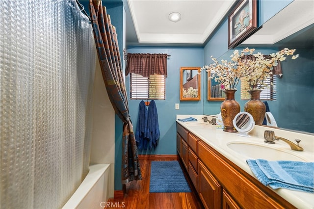 bathroom with wood-type flooring, vanity, a raised ceiling, and shower / bath combination with curtain