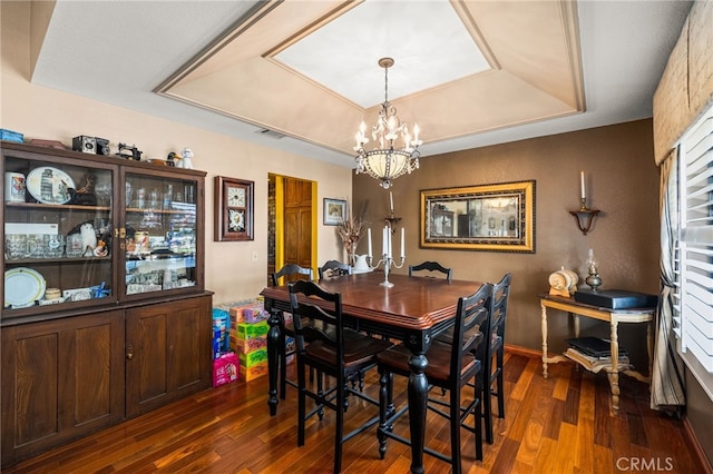 dining room featuring an inviting chandelier, a tray ceiling, and dark hardwood / wood-style floors