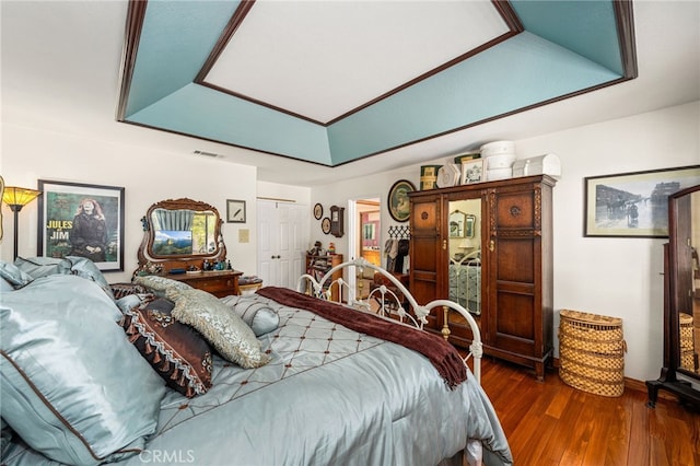 bedroom with a tray ceiling and dark hardwood / wood-style floors