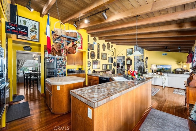 kitchen with rail lighting, dark wood-type flooring, a kitchen island, pendant lighting, and tile countertops