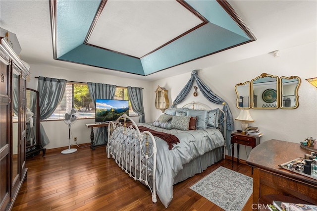 bedroom with a textured ceiling, a raised ceiling, and dark hardwood / wood-style floors