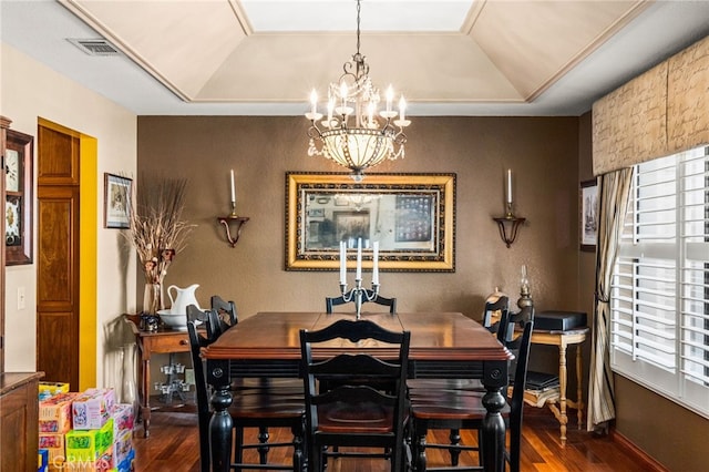 dining space with a chandelier, a raised ceiling, and dark hardwood / wood-style flooring