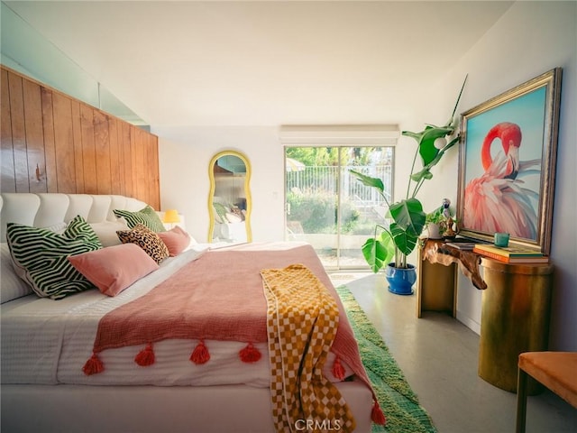 bedroom with wooden walls, access to exterior, and concrete floors