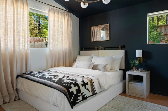 bedroom with hardwood / wood-style floors, vaulted ceiling, and multiple windows