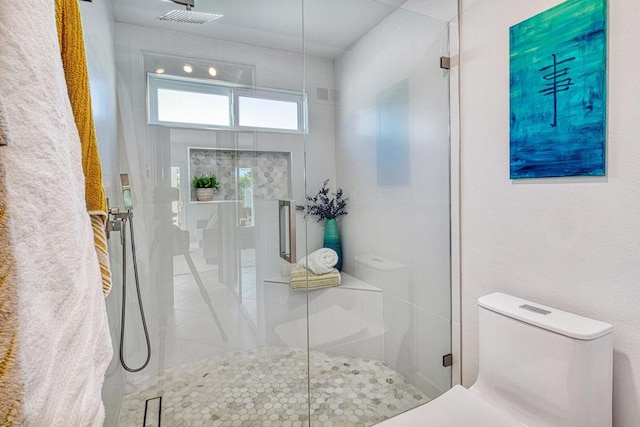 bathroom featuring a shower with shower door and toilet