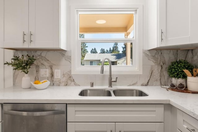 kitchen featuring sink, dishwasher, light stone countertops, white cabinets, and decorative backsplash