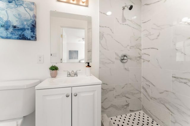 bathroom featuring vanity, a tile shower, and toilet