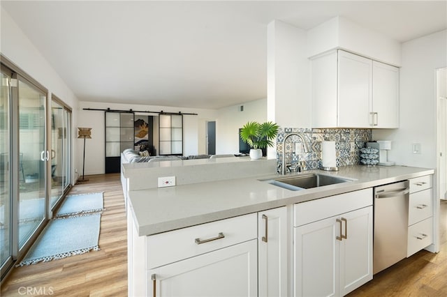 kitchen featuring dishwasher, white cabinetry, kitchen peninsula, a barn door, and light hardwood / wood-style flooring