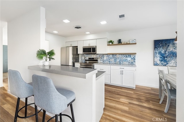 kitchen featuring a kitchen breakfast bar, white cabinetry, kitchen peninsula, and appliances with stainless steel finishes