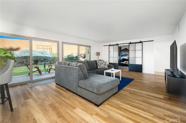 living room with a barn door and hardwood / wood-style floors