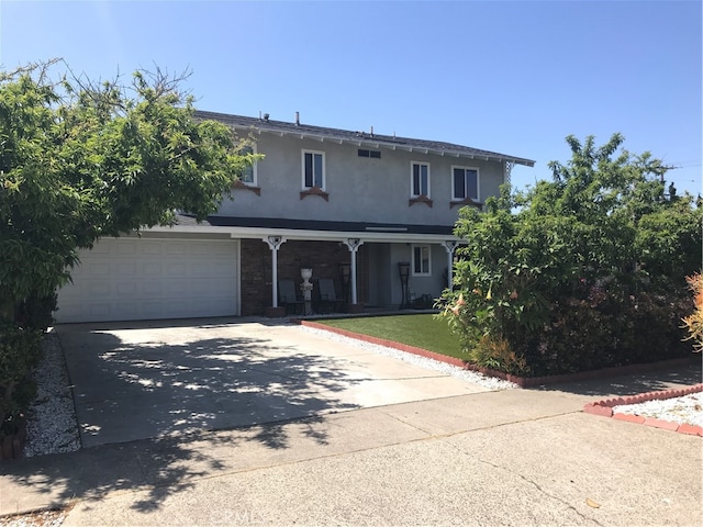 traditional-style home featuring stucco siding, covered porch, concrete driveway, a front yard, and a garage