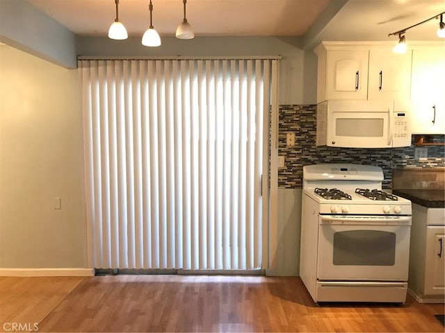 kitchen featuring dark countertops, light wood-style flooring, white appliances, and tasteful backsplash