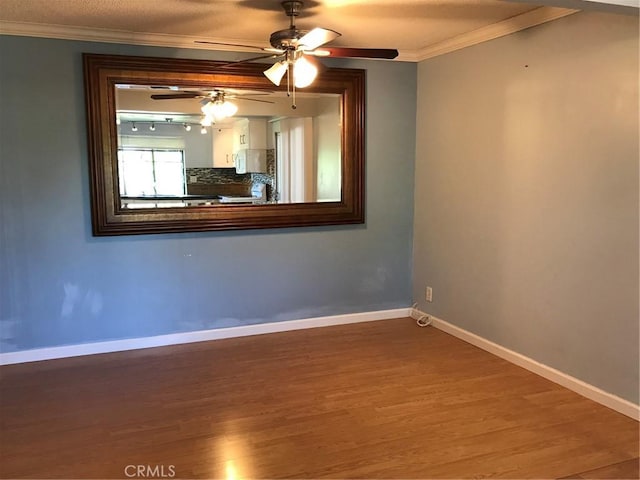 empty room featuring ceiling fan, baseboards, wood finished floors, and ornamental molding