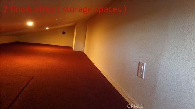 interior space featuring lofted ceiling, baseboards, and dark colored carpet