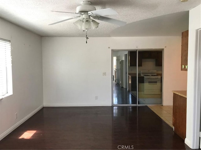 unfurnished room featuring ceiling fan, baseboards, a textured ceiling, and wood finished floors