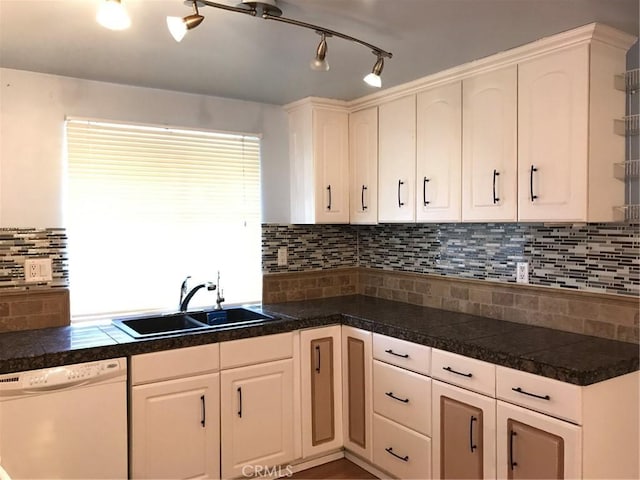 kitchen featuring white dishwasher, a sink, decorative backsplash, tile counters, and white cabinetry