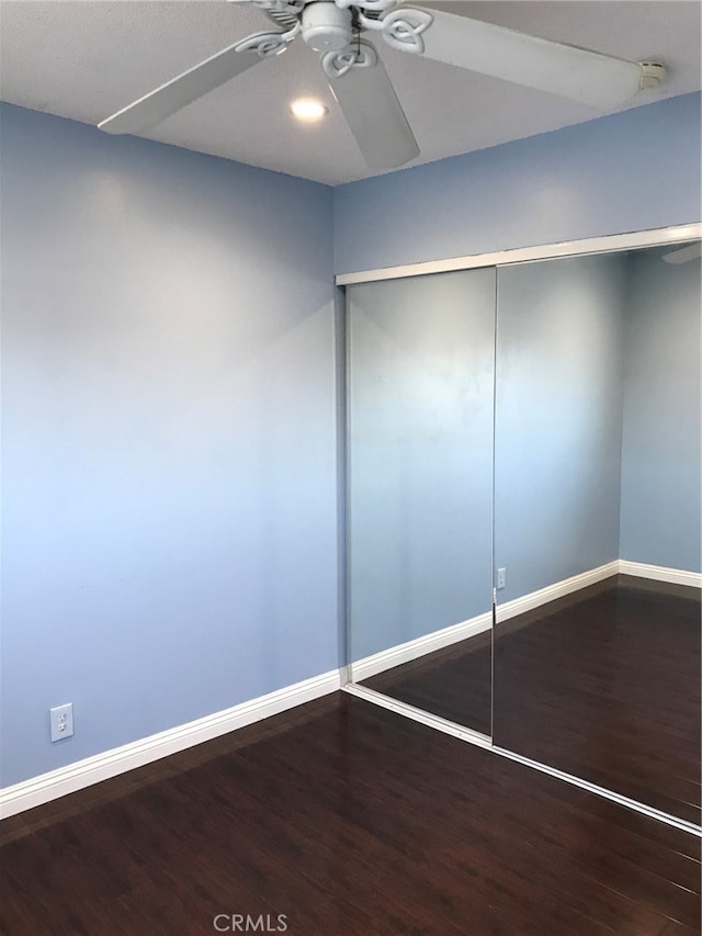 unfurnished bedroom with a closet, a ceiling fan, baseboards, and wood finished floors