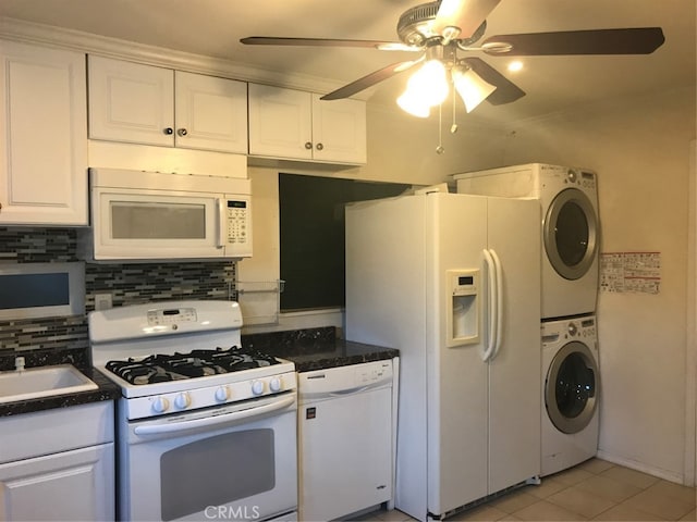 kitchen with white appliances, decorative backsplash, white cabinets, stacked washer / drying machine, and dark countertops