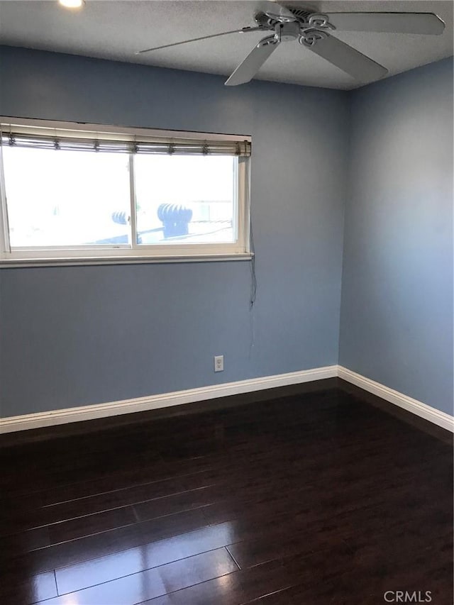 unfurnished room with dark wood finished floors, baseboards, and ceiling fan