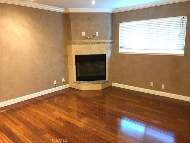 unfurnished living room featuring ornamental molding, wood finished floors, baseboards, and a tile fireplace