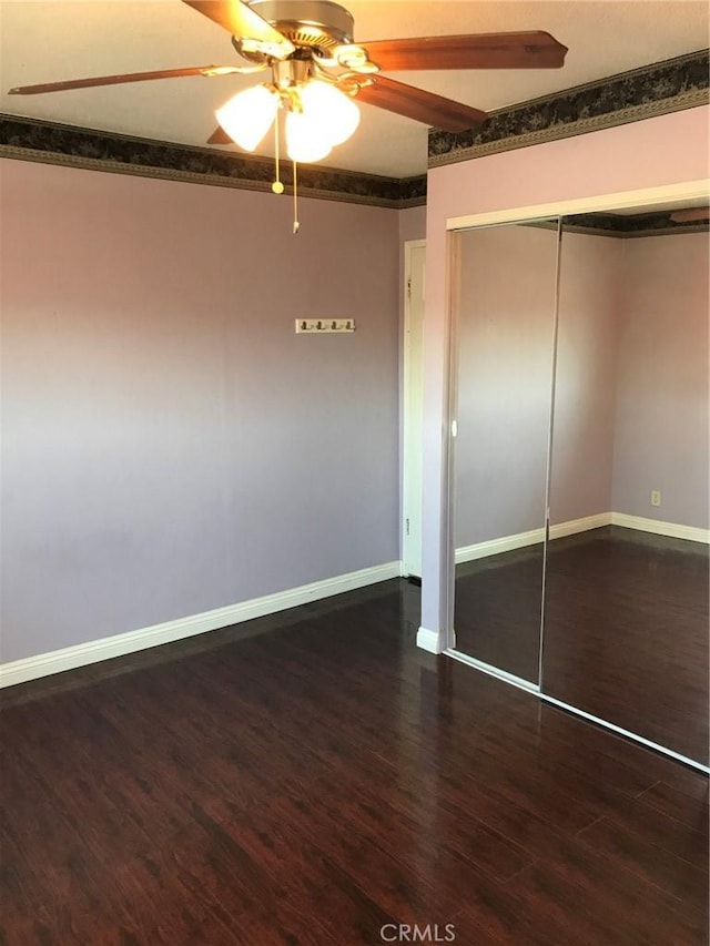 unfurnished bedroom with a closet, baseboards, wood finished floors, and a ceiling fan