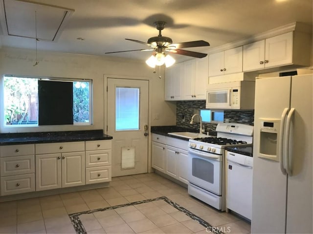 kitchen with a sink, white appliances, and white cabinetry