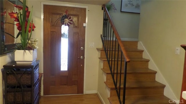 entryway featuring stairs, baseboards, and wood finished floors