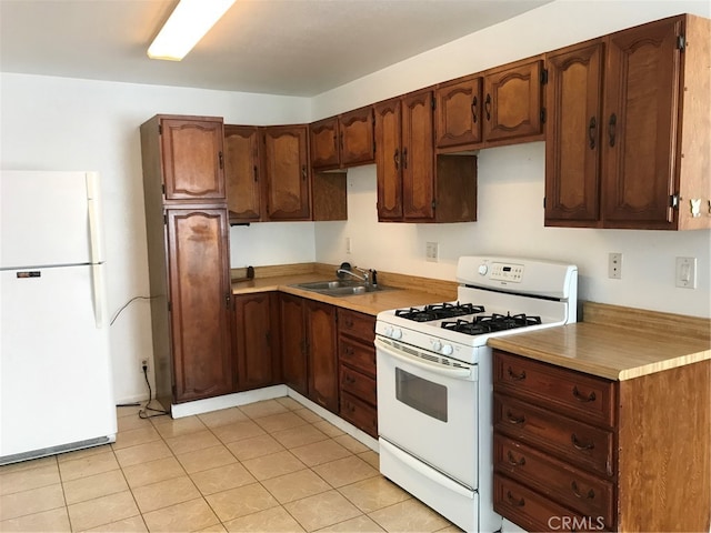 kitchen with a sink, white appliances, light tile patterned floors, and light countertops