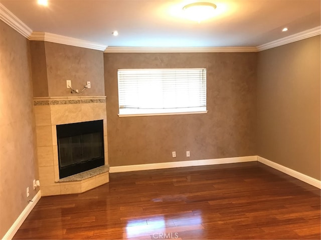 unfurnished living room with a tile fireplace, crown molding, baseboards, and wood finished floors