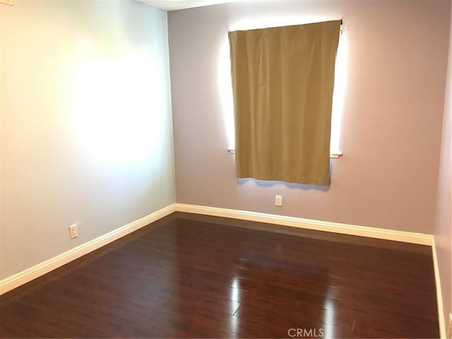 unfurnished room featuring dark wood finished floors and baseboards