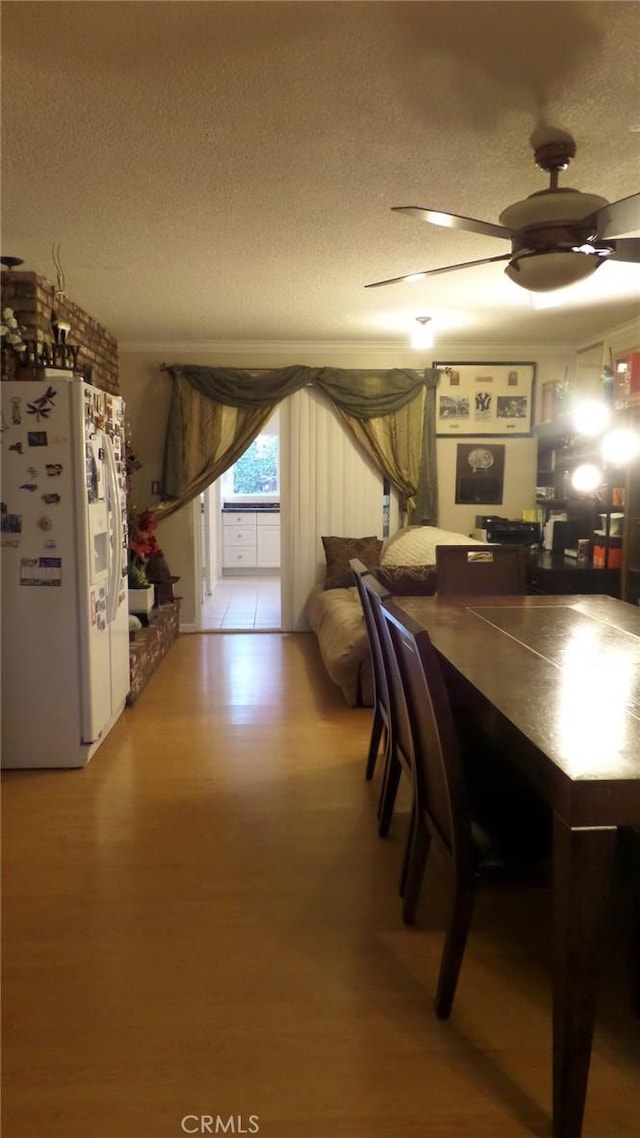 unfurnished dining area featuring a textured ceiling, light wood-type flooring, and ceiling fan