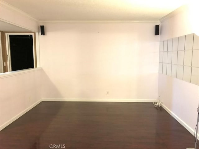 unfurnished room featuring dark wood-type flooring, baseboards, and ornamental molding