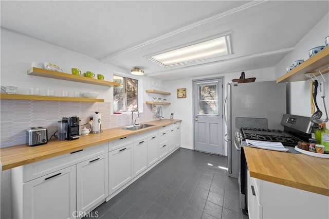 kitchen featuring gas range, white cabinetry, and wood counters