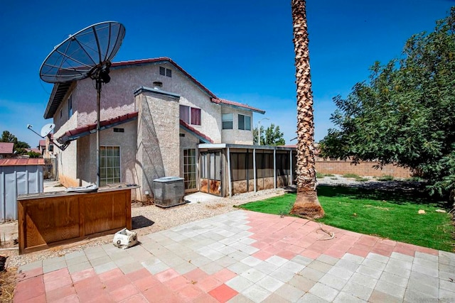 rear view of property featuring a patio, a sunroom, and a lawn