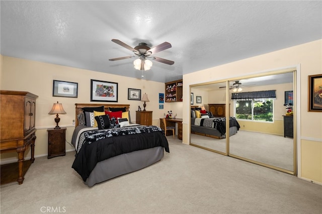 bedroom with a closet, ceiling fan, light colored carpet, and a textured ceiling