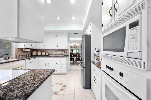 kitchen with tasteful backsplash, sink, white cabinets, an inviting chandelier, and white appliances