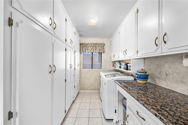 clothes washing area featuring light tile patterned floors, cabinets, and independent washer and dryer