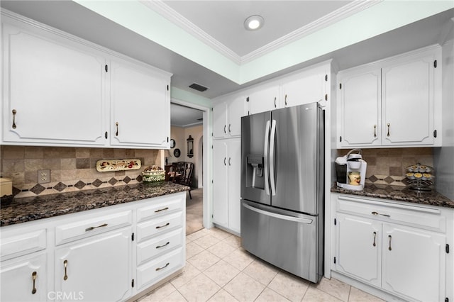 kitchen featuring dark stone countertops, white cabinets, and stainless steel fridge