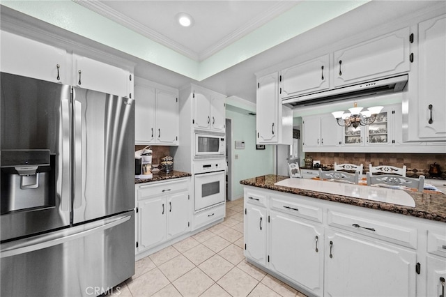 kitchen with white cabinets, ornamental molding, white appliances, dark stone counters, and decorative backsplash