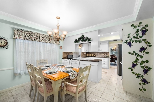 tiled dining area featuring a tray ceiling, ornamental molding, and a chandelier