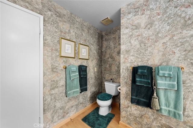 bathroom with a textured ceiling, hardwood / wood-style floors, and toilet