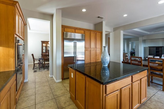 kitchen featuring a kitchen island, dark stone countertops, light tile patterned flooring, and appliances with stainless steel finishes