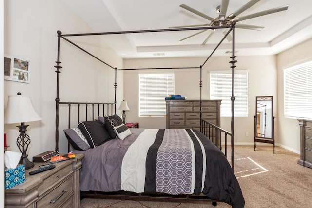 carpeted bedroom with a tray ceiling and ceiling fan