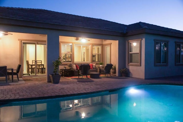 pool at dusk with an outdoor living space and a patio