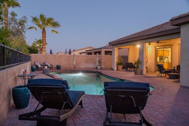 pool at dusk featuring a patio